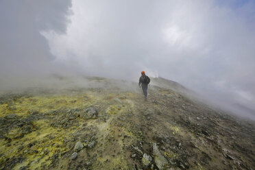 Italien, Sizilien, Gipfel des Ätna, junger Mann beim Wandern auf einem Schwefelfeld - THGF00027