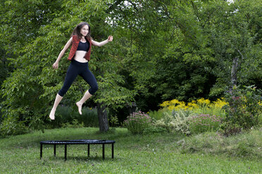 Frau springt auf Trampolin im Garten - NDF00696