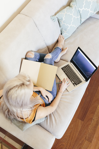 Junge Frau mit Notebook und Laptop auf der Couch zu Hause, lizenzfreies Stockfoto