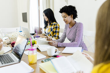 Group of female students working together at table at home - GIOF03369