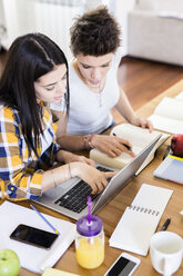 Zwei Studentinnen arbeiten gemeinsam an einem Tisch zu Hause - GIOF03383