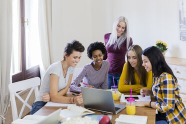 Group of female students sharing laptop at table at home - GIOF03385