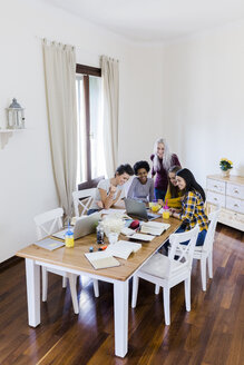 Gruppe von Studentinnen teilt sich einen Laptop am Tisch zu Hause - GIOF03387