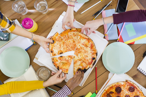Gruppe junger Frauen, die sich zu Hause eine Pizza teilen, lizenzfreies Stockfoto