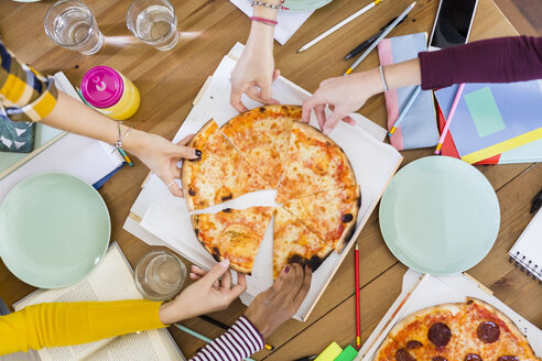 Gruppe junger Frauen, die sich zu Hause eine Pizza teilen - GIOF03396