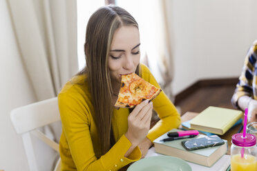 Junge Frau zu Hause beim Lernen und Pizza essen - GIOF03397