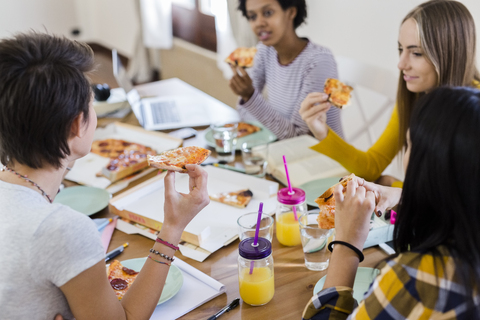 Group of young women at home studying and having pizza stock photo
