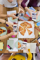 Gruppe junger Frauen, die zu Hause mit dem Handy fotografieren und sich eine Pizza teilen - GIOF03401