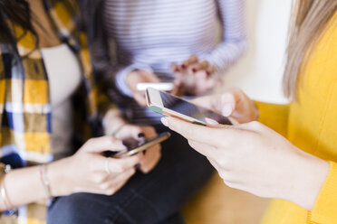 Hands of three women using smartphones - GIOF03414