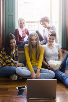 Gruppe von Freundinnen, die gemeinsam zu Hause auf einen Laptop schauen - GIOF03416