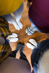 Close-up of feet of five women standing on wooden floor - GIOF03417
