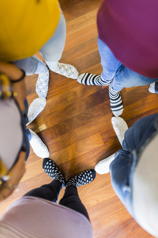 Nahaufnahme der Füße von fünf Frauen, die auf einem Holzboden stehen, lizenzfreies Stockfoto