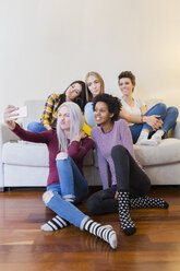 Happy female friends taking a selfie in living room - GIOF03424