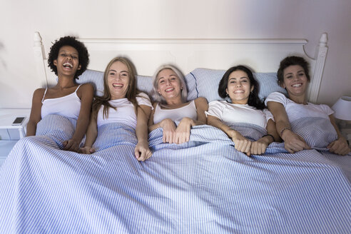 Porträt von glücklichen Freundinnen, die Seite an Seite im Bett liegen - GIOF03435