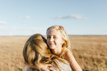 Portrait of smiling daughter hugging mother at a field - JPF00287
