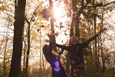 Glückliches Paar im Wald im Herbst wirft Blätter in die Luft - FCF01318