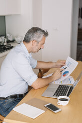 Mann, der Daten analysiert und einen Laptop im Home Office benutzt - ALBF00258