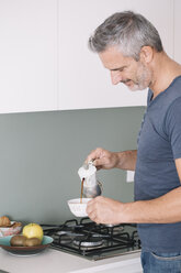 Älterer Mann in der Küche gießt eine Tasse Kaffee ein - ALBF00265