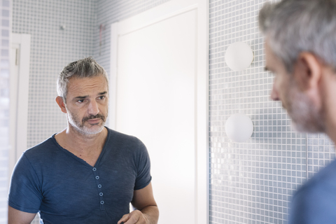 Mature man looking in bathroom mirror stock photo