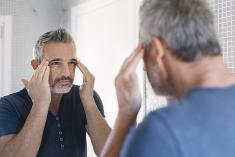 Mature man looking in bathroom mirror stock photo