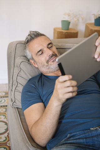 Entspannter reifer Mann zu Hause mit Tablet, lizenzfreies Stockfoto