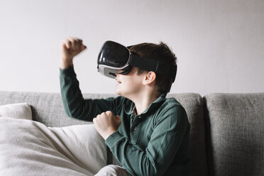 Boy sitting on the couch in the living room using Virtual Reality Glasses - ALBF00306