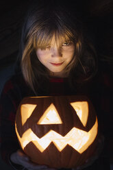Porträt eines lächelnden Mädchens mit beleuchteter Jack O'Lantern an Halloween - ALBF00313