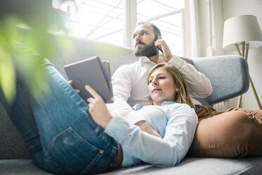 Couple using tablet and cell phone on couch - JOSF01911