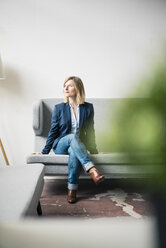 Geschäftsfrau sitzt auf einer Couch in einer Büro-Lounge - JOSF01926