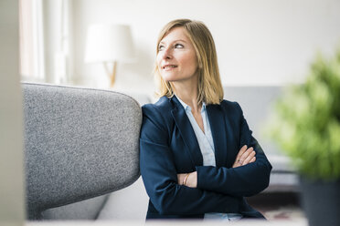 Smiling businesswoman sitting on couch in office lounge - JOSF01927