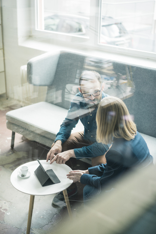 Businessman and businesswoman with tablet discussing in office lounge stock photo