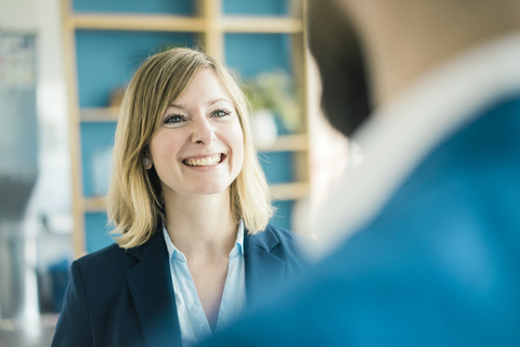 Geschäftsfrau lächelt Geschäftsmann im Büro an, lizenzfreies Stockfoto