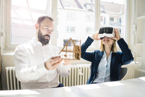 Frau und Mann mit Hausmodell und VR-Brille im Büro - JOSF01934