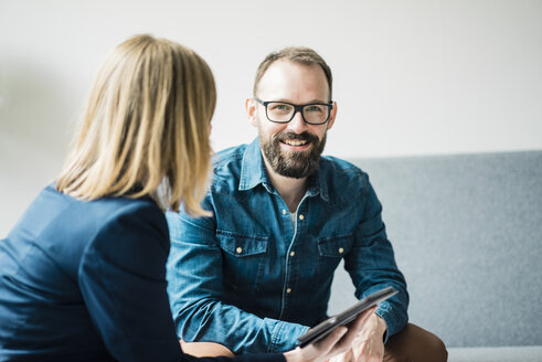 Smiling businessman and businesswoman in office lounge - JOSF01935