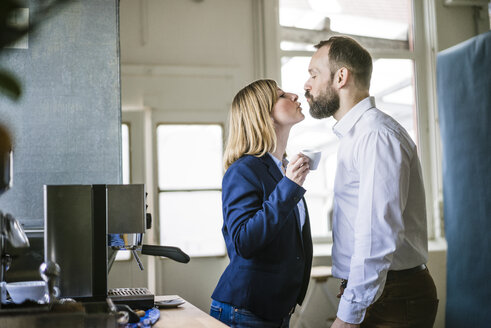 Geschäftsmann küsst Geschäftsfrau im Büro - JOSF01940
