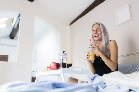 Glückliche junge Frau beim Frühstück im Bett, lizenzfreies Stockfoto