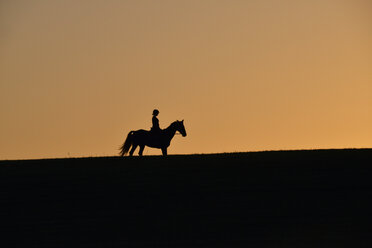Silhouette einer Reiterin bei Sonnenuntergang - GNF01422