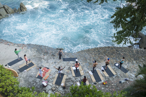 Mexico, Mismaloya, instructor with yoga class at ocean front - ABAF02182