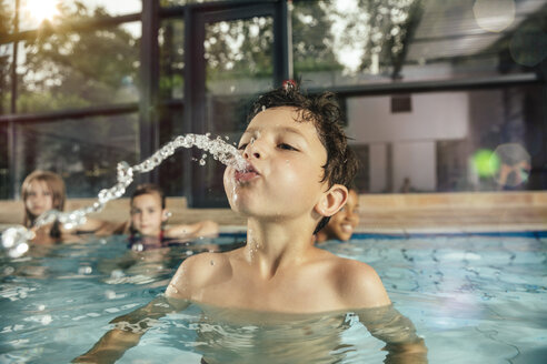 Junge mit Freunden im Hallenbad spuckt Wasser - MFF04159