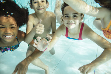 Porträt von glücklichen Kindern, die im Schwimmbad unter Wasser schwimmen - MFF04172