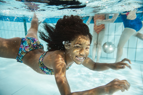 Porträt eines lächelnden Mädchens unter Wasser im Schwimmbad, lizenzfreies Stockfoto