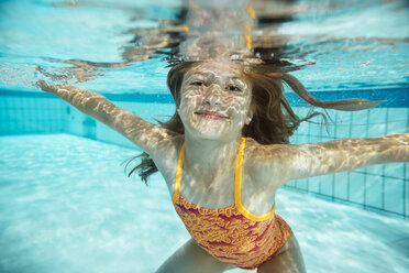 Porträt eines lächelnden Mädchens unter Wasser im Schwimmbad - MFF04175