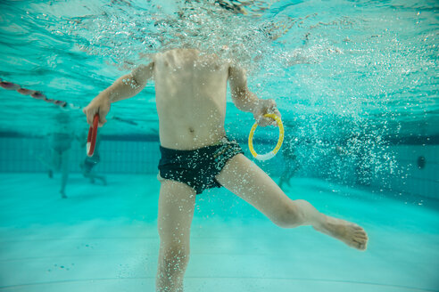 Junge hält zwei Tauchringe unter Wasser im Schwimmbad - MFF04182