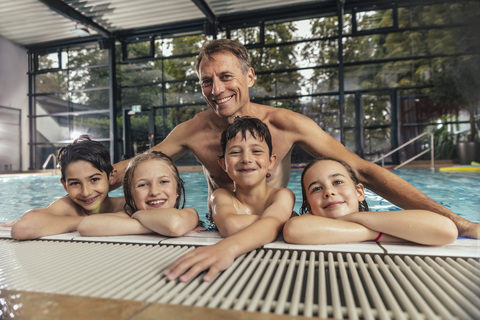 Porträt von lächelnden Kindern mit Schwimmlehrer im Hallenbad, lizenzfreies Stockfoto