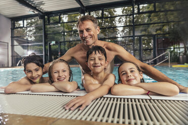 Portrait of smiling children with instructor in indoor swimming pool - MFF04206