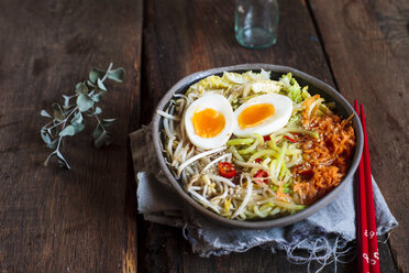 Schüssel mit glutenfreier Udon-Nudelsuppe mit Karotten, Chinakohl, Zoodles, Mungobohnensprossen und gekochtem Ei - SBDF03383