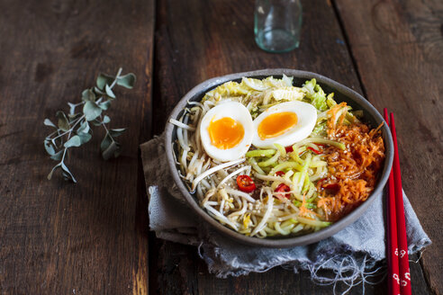 Schüssel mit glutenfreier Udon-Nudelsuppe mit Karotten, Chinakohl, Zoodles, Mungobohnensprossen und gekochtem Ei - SBDF03383