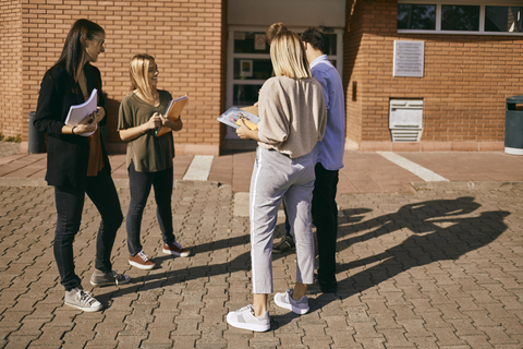 Group of students standing outdoors with documents stock photo