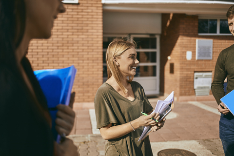 Smiling students standing outdoors with documents stock photo