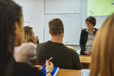 Lecturer smiling at students in auditorium at university - ZEDF01005